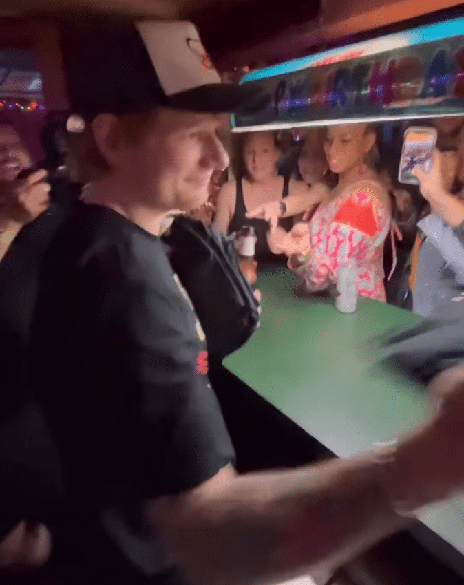 Ed Sheeran passes out t-shirts to happy fans at the bub. 