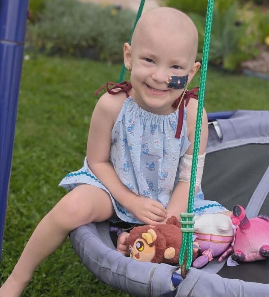 tessa sitting on a swing with her toys