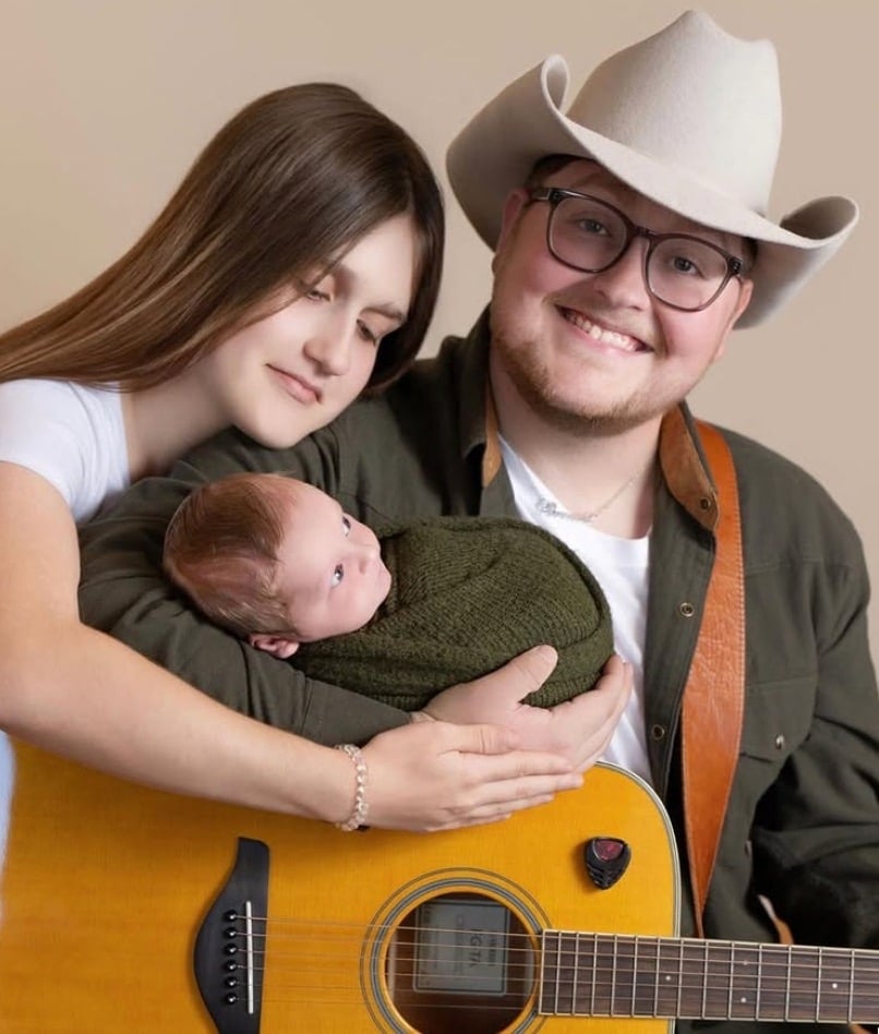 Christian Brown posing with his wife and their newborn son, Isaiah 